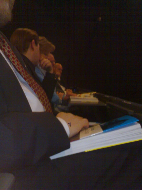 two people sitting in a row at a table with books