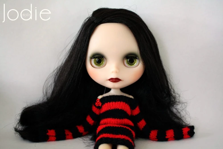 a doll that has long hair and wears black hair with stripes on it