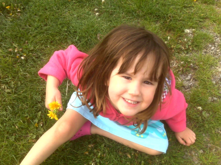 a little girl laying on the ground with a flower