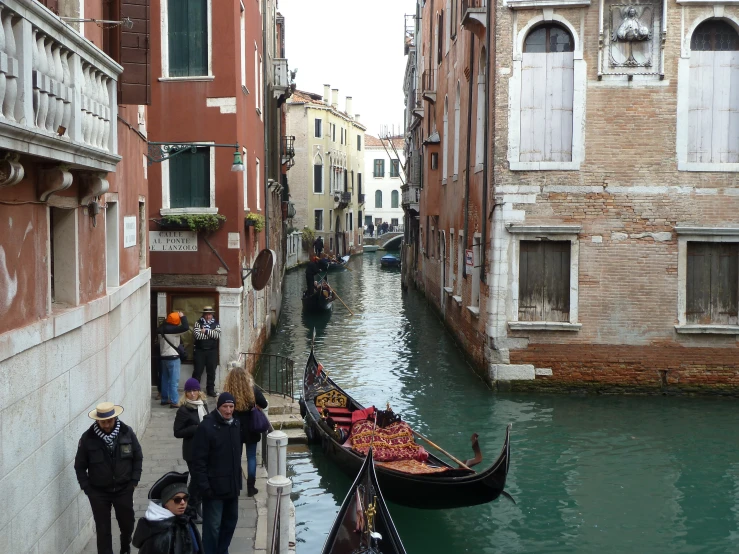 people are standing around at the edge of the water while a boat is parked next to them