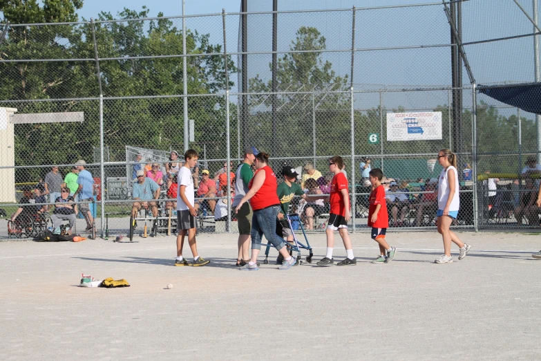 a group of young people standing next to a baseball field