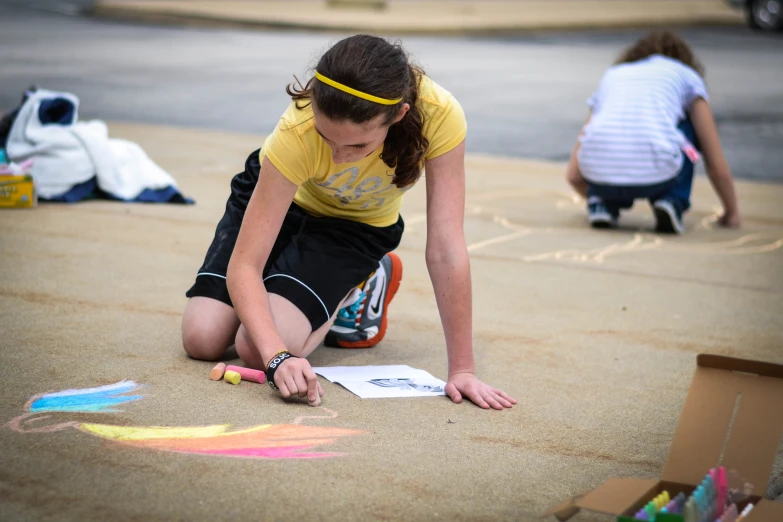  draws pictures in the sand with chalk on the sidewalk