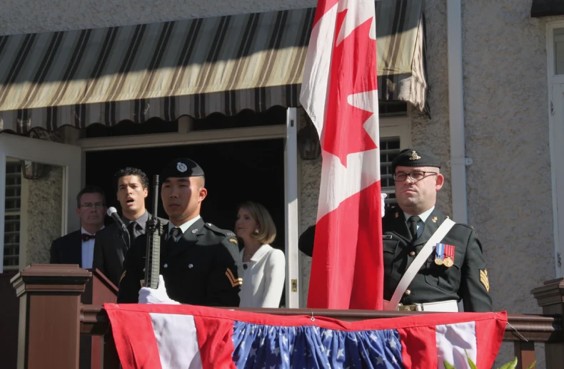 people stand behind a podium as a soldier stands at attention