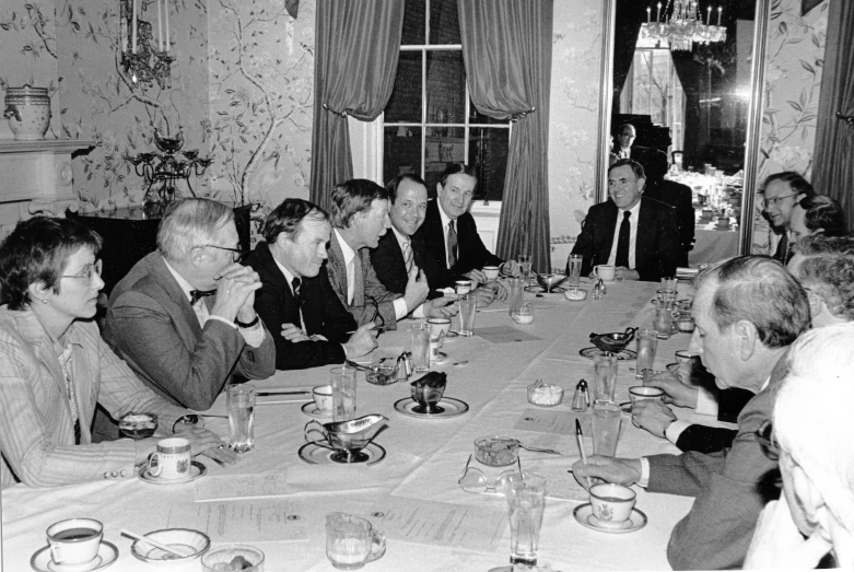 a group of men sitting around a table talking