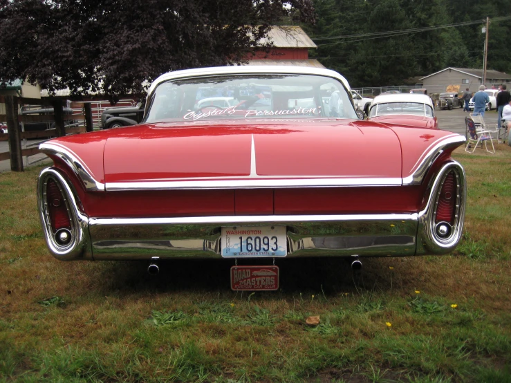 an antique red car parked in the grass