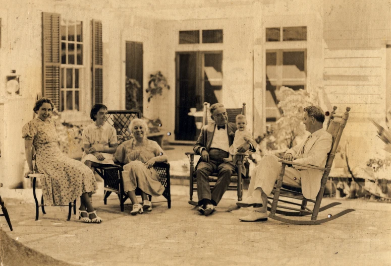 old pograph of children in rocking chairs outside a house