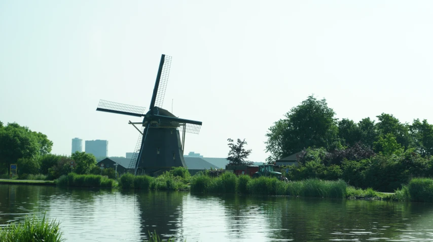 a windmill sits on the edge of a lake