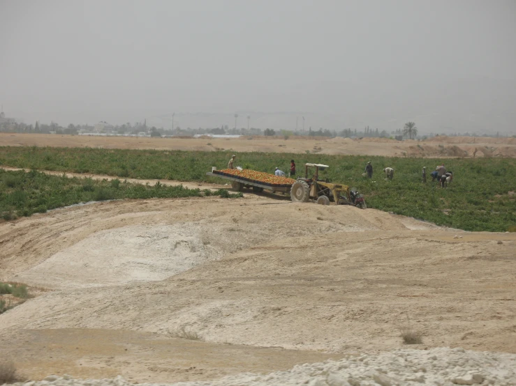 an antique tractor is shown in a field as people stand around