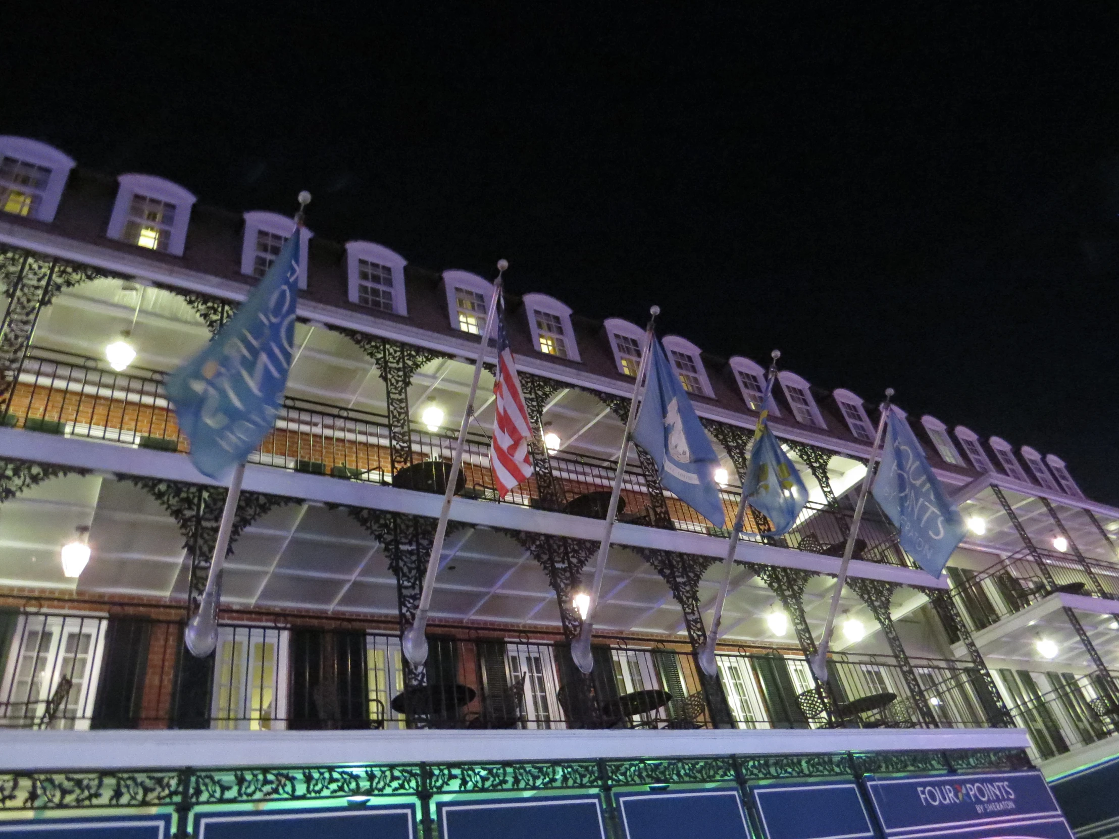 some flags are outside of a building at night