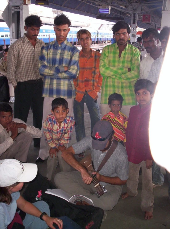 several men pose for the camera in front of some boys