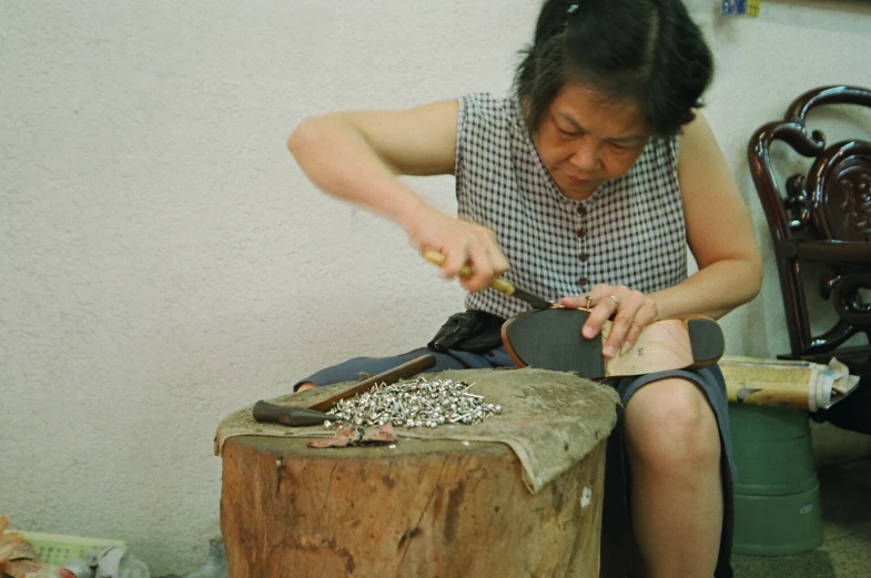 a woman sitting down working with a shoe