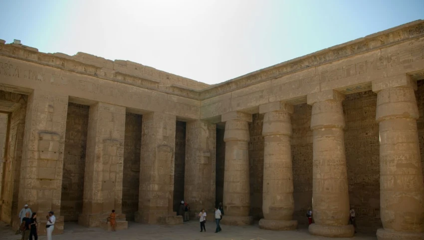 several people walk between three very large stone structures