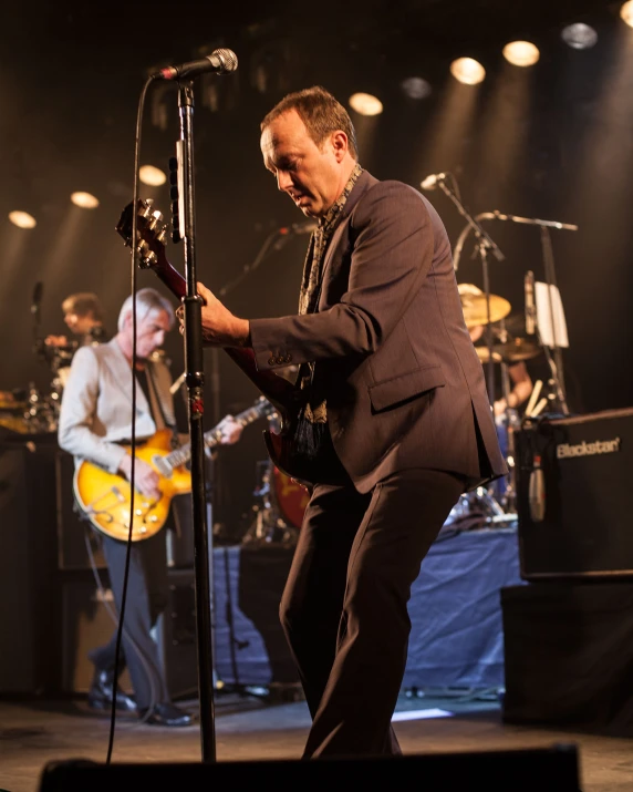 a man playing a guitar while standing in front of some microphones