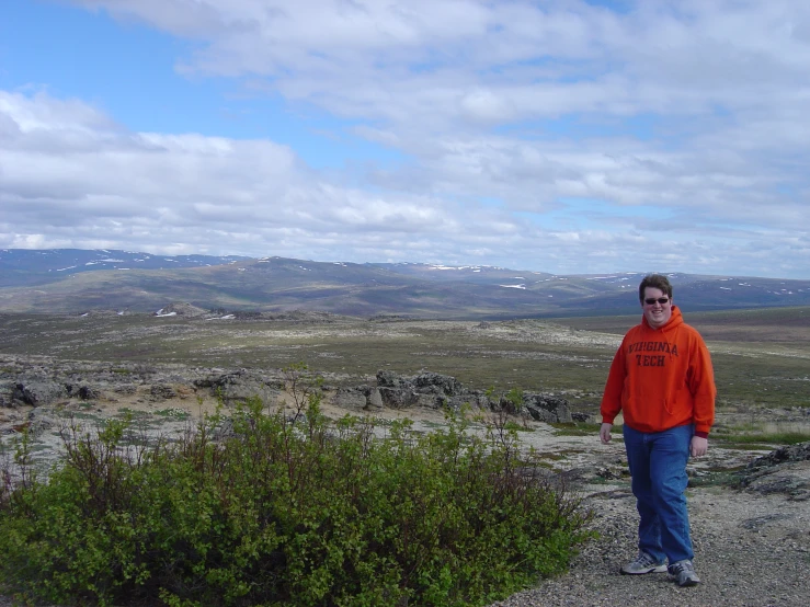 the young man is standing near plants and rocks