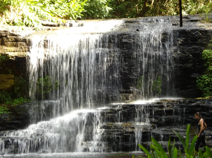 two people under the waterfall and one man is walking down