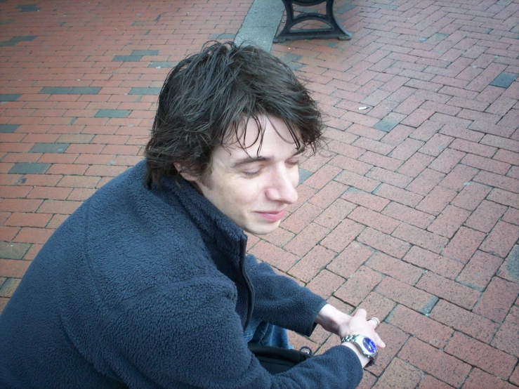 a man sitting down outside wearing a blue coat