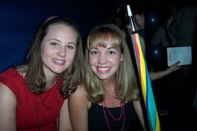 two women smiling and posing with a large toothbrush