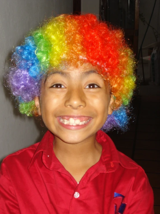 a child wearing rainbow colored hair stands in a room