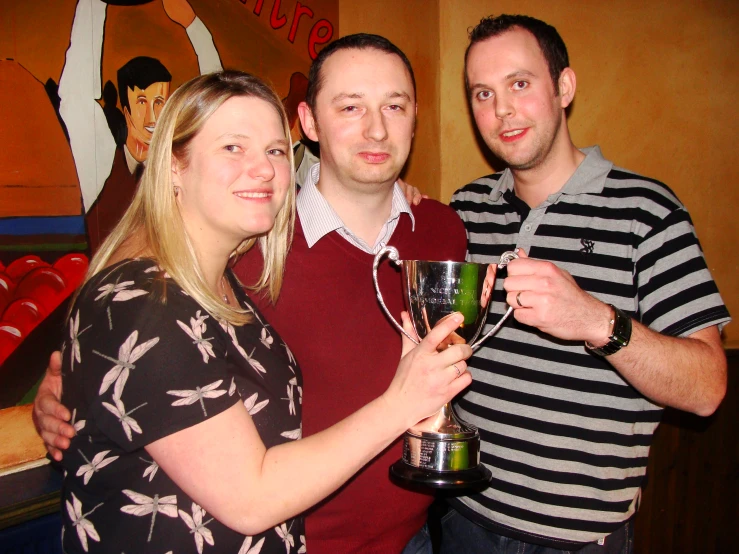 a woman holding a cup while standing next to a man