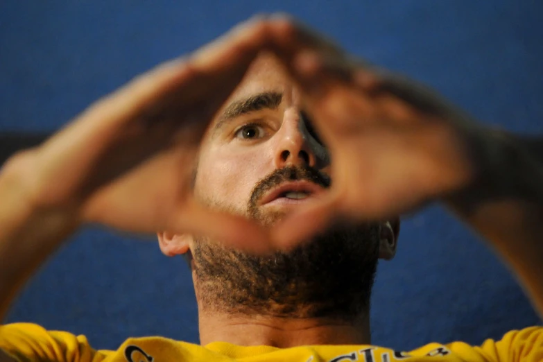 man looking upward and making a heart shaped gesture