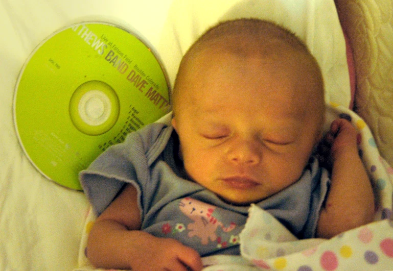a baby sleeping in a crib next to a green disc