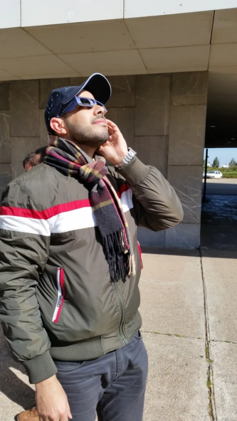 a man on his phone wearing a scarf and jacket