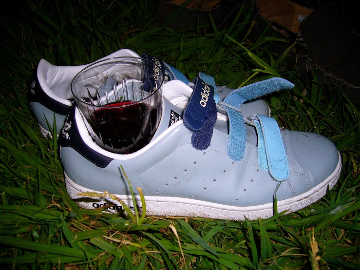 a pair of tennis shoes with blue laces and a glass of wine