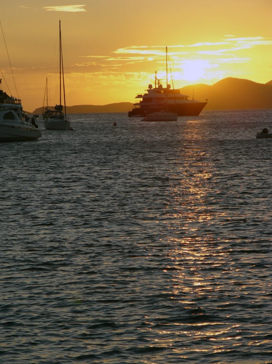 three boats are sailing in the water and one has a big white boat in the distance