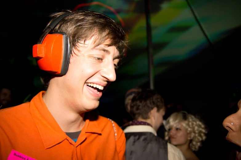 a young man laughing with headphones on his ears