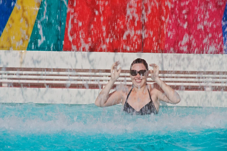 a woman in sunglasses is swimming in a pool