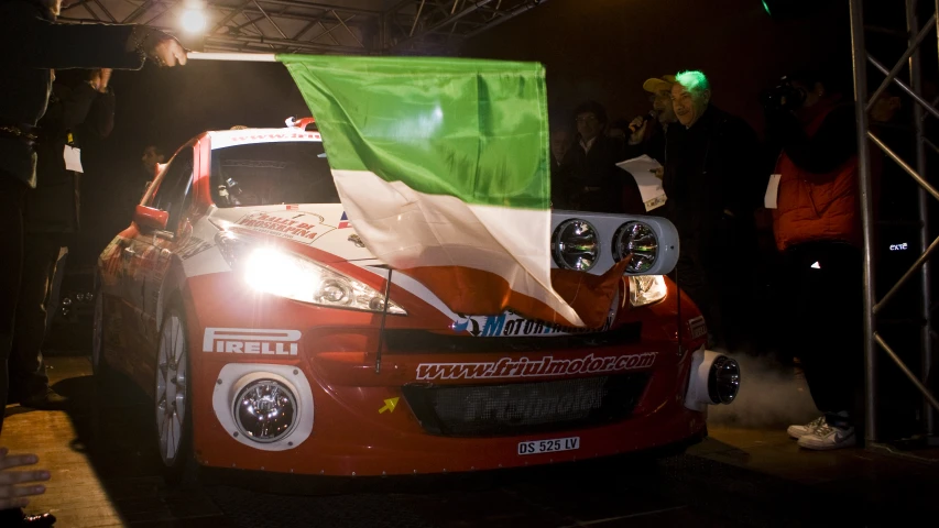 a car is on a stage with an italian flag on its hood