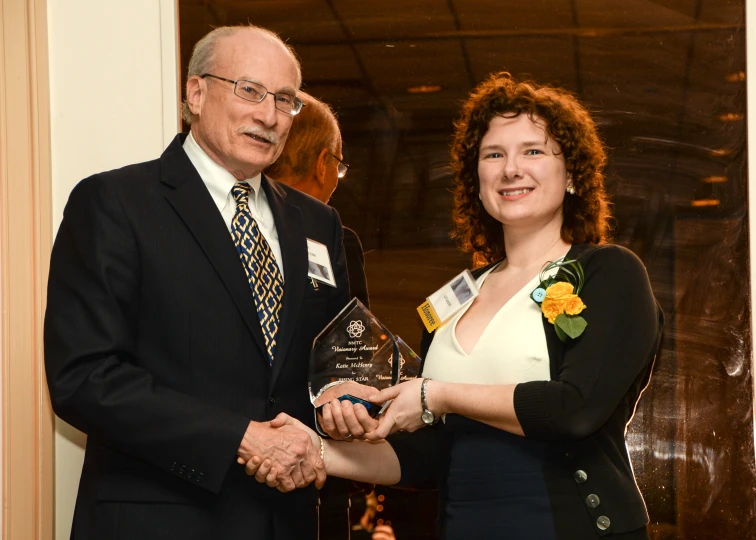 an old man receiving a trophy from a woman