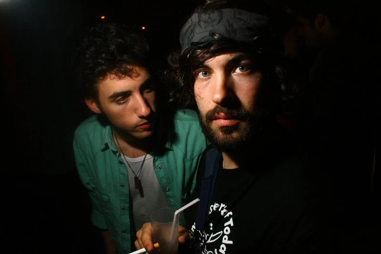 two men sitting next to each other in a dark room