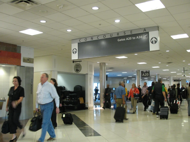 people with luggage walking through an airport lobby