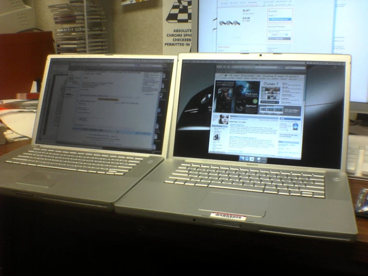 two laptop computers sitting side by side on top of a desk