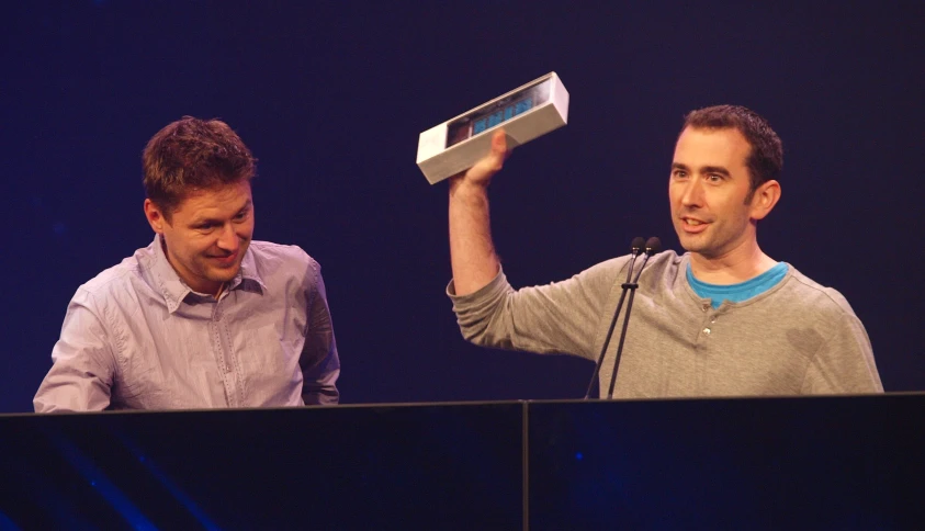 two men holding up video game equipment on stage