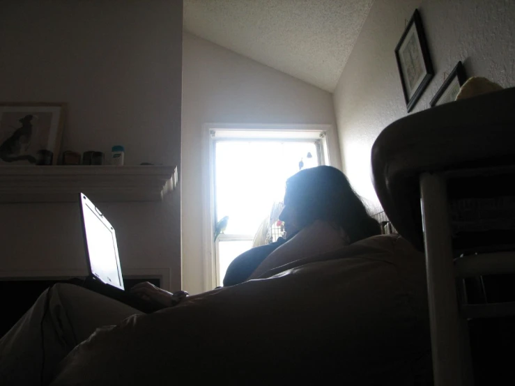 a woman sitting on her back looking at her laptop