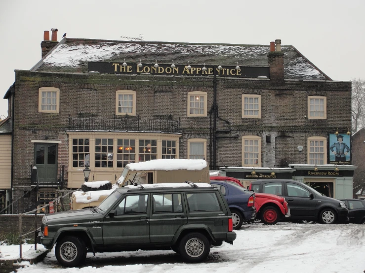 cars parked in front of a brick building covered in snow