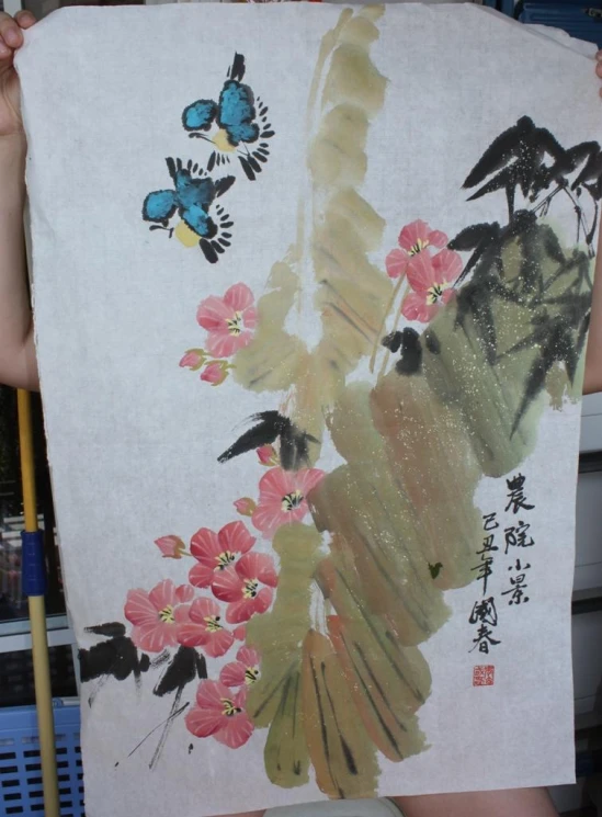 an image of someone holding a piece of art with birds and flowers