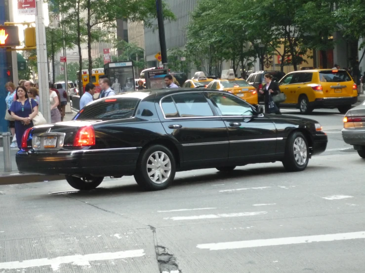 black car stopped on city road for people to cross it