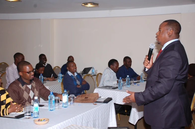 a man standing at a microphone giving a speech to a group