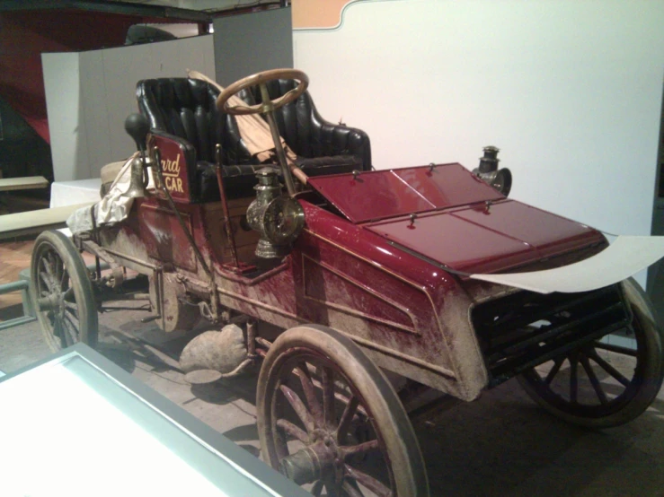 a very old style car is displayed at a museum