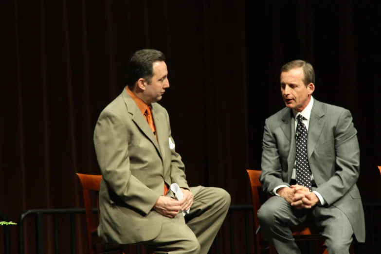 two men in suits sit on the ground