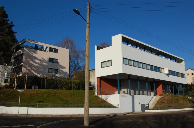 a white building with windows sits behind an orange wall