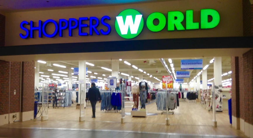 a department store with people walking out and a sign for the shoppers world