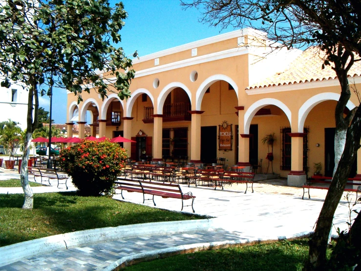 a large yellow building with a few red umbrellas