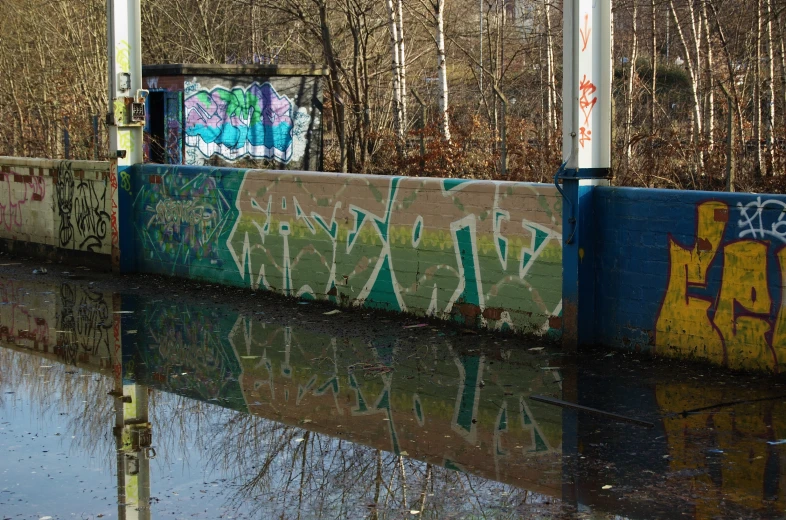 a graffiti wall on a waterway with water surrounding it