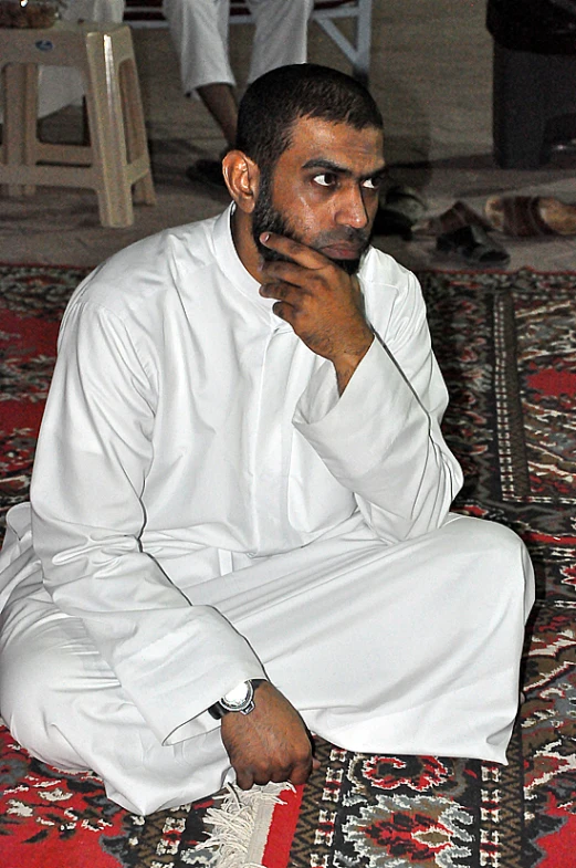 a man wearing white sitting on the floor