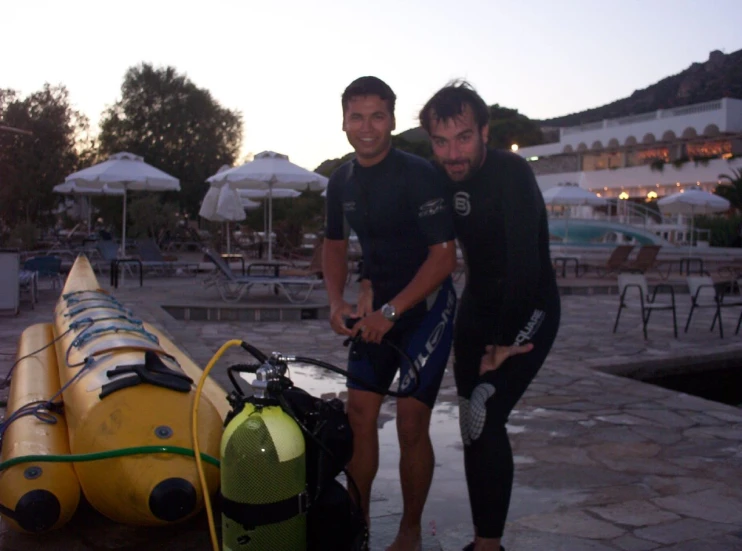 two young men standing near some buoys and barrels