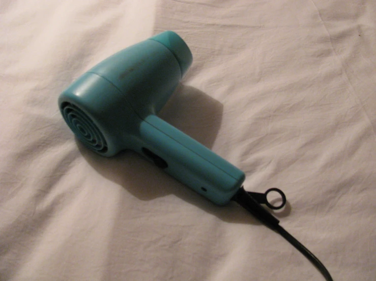 blue hair dryer sitting on top of a white sheet